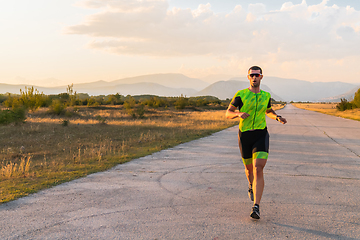 Image showing Triathlete in professional gear running early in the morning, preparing for a marathon, dedication to sport and readiness to take on the challenges of a marathon.