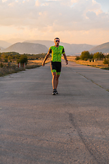 Image showing Triathlete in professional gear running early in the morning, preparing for a marathon, dedication to sport and readiness to take on the challenges of a marathon.