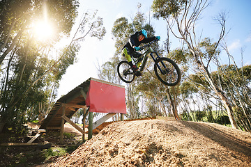Image showing Bike, jump and man with ramp, outdoor and speed for sports, race or adventure in summer, woods or nature. Extreme cycling, person and training on trail, competition or challenge for fitness in forest