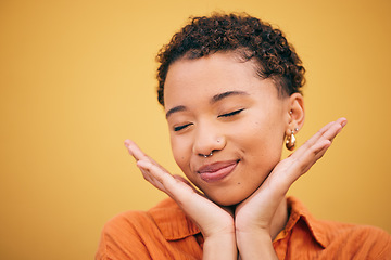 Image showing Happy, woman relax and hands on face in studio with smile and confidence feeling cute. Orange background, young and African female person with trendy, modern and student fashion with mockup space