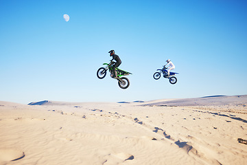 Image showing Motorbike, desert race and jump in air for competition, stunt and outdoor for performance, goal and speed. Motorcycle athlete, dunes and ramp in nature, fast or together for contest by sky background