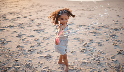 Image showing Girl kid, beach and outdoor with bubbles, playing and freedom with air, games and smile in nature. Young female child, soap and water with plastic toys in wind, summer sunshine and happy on vacation