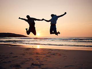 Image showing Beach, sunset and silhouette of couple jump, holding hands and enjoy fun quality time together on summer holiday. Energy, ocean sea and excited man, woman or people celebrate Australia vacation