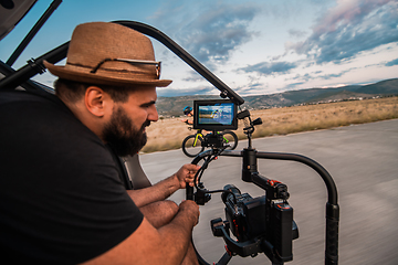 Image showing A videographer recording a triathlete riding his bike preparing for an upcoming marathon.Athlete's physical endurance and the dedication required to succeed in the sport.