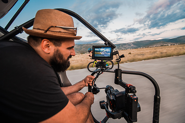 Image showing A videographer recording a triathlete riding his bike preparing for an upcoming marathon.Athlete's physical endurance and the dedication required to succeed in the sport.