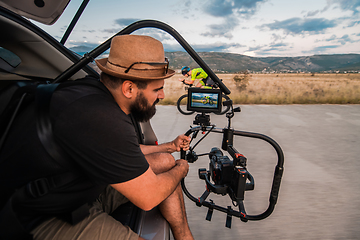 Image showing A videographer recording a triathlete riding his bike preparing for an upcoming marathon.Athlete's physical endurance and the dedication required to succeed in the sport.