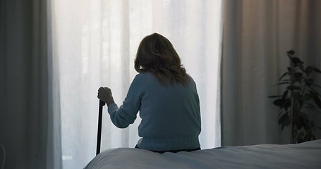 Image showing Thinking, sad and window with old woman and walking stick in bedroom for wellness, retirement and healthcare. Depression, mental health and nursing home with patient with a disability for support