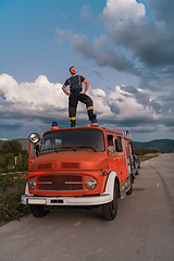 Image showing The firefighter standing confidently on the fire truck, ready to respond to any emergency.