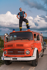 Image showing The firefighter standing confidently on the fire truck, ready to respond to any emergency.