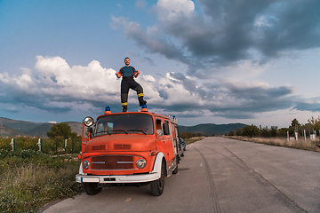 Image showing The firefighter standing confidently on the fire truck, ready to respond to any emergency.