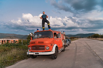 Image showing The firefighter standing confidently on the fire truck, ready to respond to any emergency.