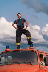 Image showing The firefighter standing confidently on the fire truck, ready to respond to any emergency.