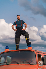 Image showing The firefighter standing confidently on the fire truck, ready to respond to any emergency.