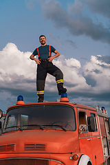 Image showing The firefighter standing confidently on the fire truck, ready to respond to any emergency.