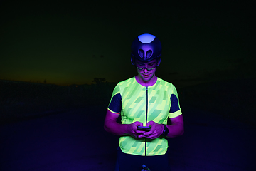 Image showing A triathlete using a smartphone while taking a break from a hard night's cycling training