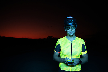 Image showing A triathlete using a smartphone while taking a break from a hard night's cycling training