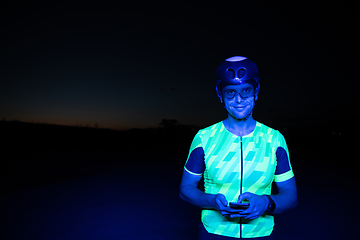 Image showing A triathlete using a smartphone while taking a break from a hard night's cycling training