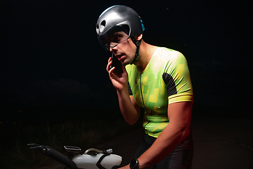 Image showing A triathlete using a smartphone while taking a break from a hard night's cycling training