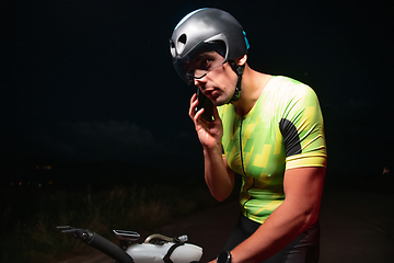 Image showing A triathlete using a smartphone while taking a break from a hard night's cycling training