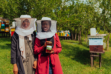 Image showing Portrait of a Arab investitors in the beekeeping department of a honey farm holding a jar of honey in her hand