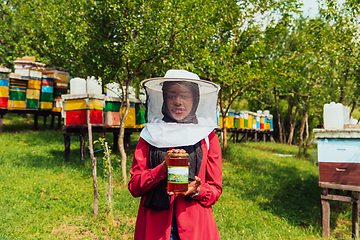 Image showing Portrait of Arab investitor in the beekeeping department of a honey farm holding a jar of honey in her hand