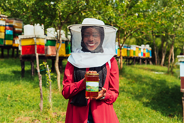 Image showing Portrait of Arab investitor in the beekeeping department of a honey farm holding a jar of honey in her hand