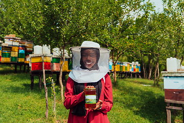 Image showing Portrait of Arab investitor in the beekeeping department of a honey farm holding a jar of honey in her hand