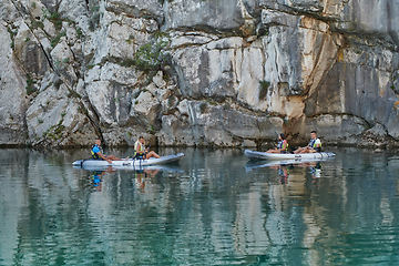 Image showing A group of friends enjoying having fun and kayaking while exploring the calm river, surrounding forest and large natural river canyons