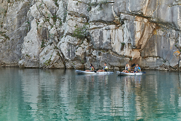 Image showing A group of friends enjoying having fun and kayaking while exploring the calm river, surrounding forest and large natural river canyons