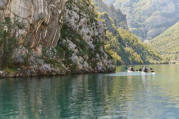 Image showing A group of friends enjoying having fun and kayaking while exploring the calm river, surrounding forest and large natural river canyons