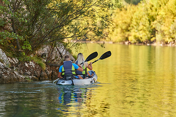 Image showing A young couple enjoying an idyllic kayak ride in the middle of a beautiful river surrounded by forest greenery