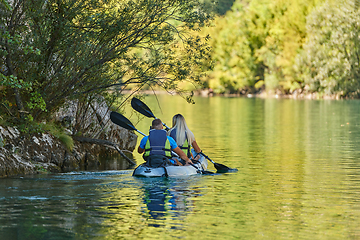 Image showing A young couple enjoying an idyllic kayak ride in the middle of a beautiful river surrounded by forest greenery