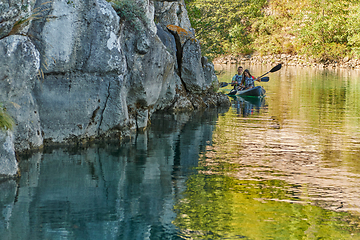 Image showing A young couple enjoying an idyllic kayak ride in the middle of a beautiful river surrounded by forest greenery