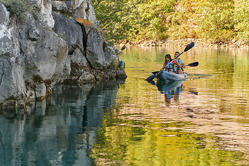 Image showing A young couple enjoying an idyllic kayak ride in the middle of a beautiful river surrounded by forest greenery