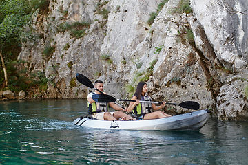 Image showing A young couple enjoying an idyllic kayak ride in the middle of a beautiful river surrounded by forest greenery