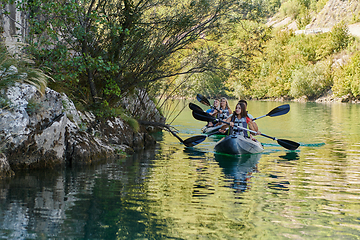 Image showing A group of friends enjoying having fun and kayaking while exploring the calm river, surrounding forest and large natural river canyons