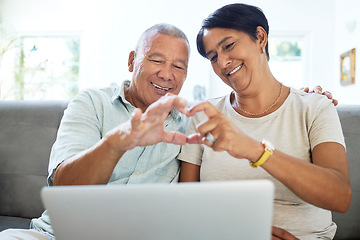 Image showing Mature couple, heart hands and laptop on home sofa for video call, streaming and internet. A happy man and woman together on a couch with technology for communication, social media emoji or love