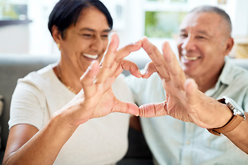 Image showing Mature couple, heart hands and love on home sofa for connection, marriage and bond. A happy man and woman together on a couch with emoji, shape or symbol for commitment, trust or health and wellness