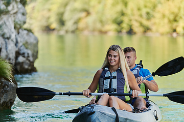 Image showing A young couple enjoying an idyllic kayak ride in the middle of a beautiful river surrounded by forest greenery