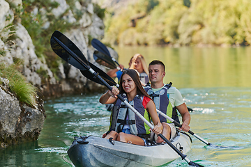 Image showing A group of friends enjoying having fun and kayaking while exploring the calm river, surrounding forest and large natural river canyons