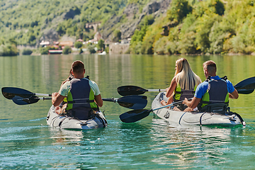 Image showing A group of friends enjoying having fun and kayaking while exploring the calm river, surrounding forest and large natural river canyons