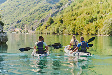 Image showing A group of friends enjoying having fun and kayaking while exploring the calm river, surrounding forest and large natural river canyons