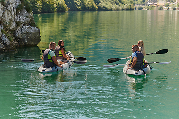 Image showing A group of friends enjoying having fun and kayaking while exploring the calm river, surrounding forest and large natural river canyons