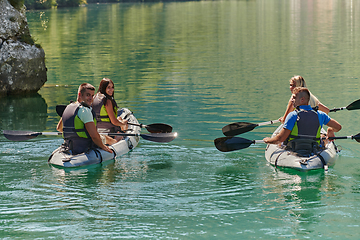 Image showing A group of friends enjoying having fun and kayaking while exploring the calm river, surrounding forest and large natural river canyons