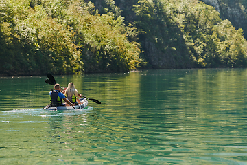 Image showing A young couple enjoying an idyllic kayak ride in the middle of a beautiful river surrounded by forest greenery