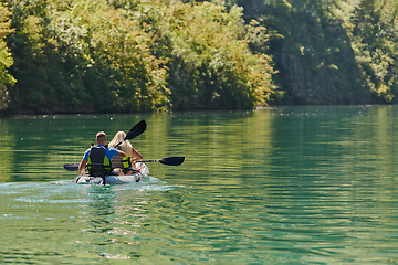 Image showing A young couple enjoying an idyllic kayak ride in the middle of a beautiful river surrounded by forest greenery