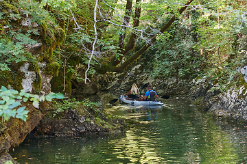 Image showing A young couple enjoying an idyllic kayak ride in the middle of a beautiful river surrounded by forest greenery