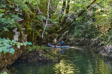 Image showing A young couple enjoying an idyllic kayak ride in the middle of a beautiful river surrounded by forest greenery