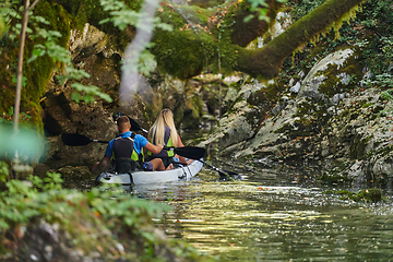 Image showing A young couple enjoying an idyllic kayak ride in the middle of a beautiful river surrounded by forest greenery