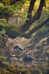 Image showing A group of friends enjoying having fun and kayaking while exploring the calm river, surrounding forest and large natural river canyons